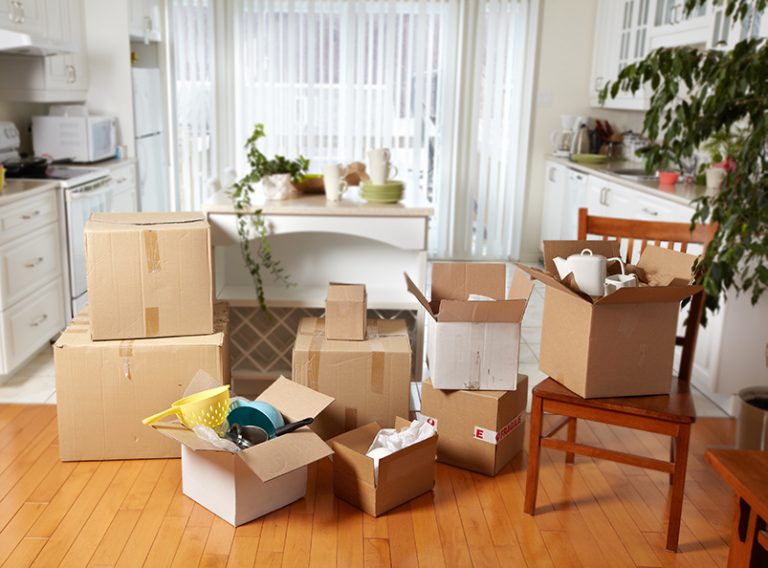 Packed moving boxes stacked in a kitchen and dining area
