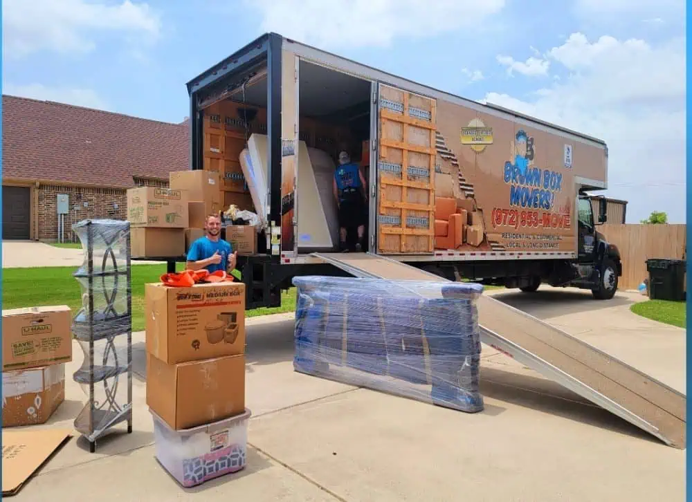 Movers loading furniture into a Brown Box Movers truck