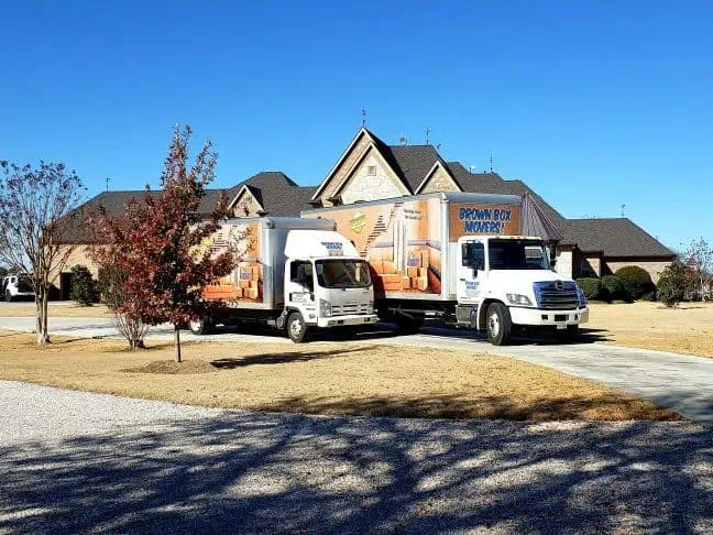 Brown Box Movers truck parked outside a family home