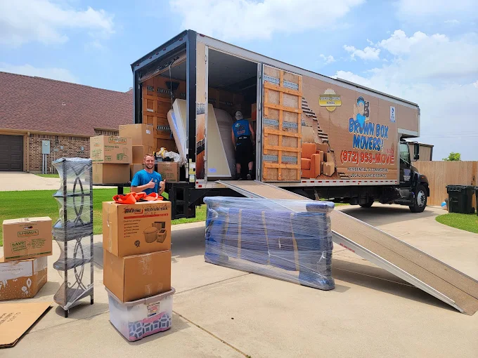 Movers loading furniture and boxes into an open Brown Box Movers truck
