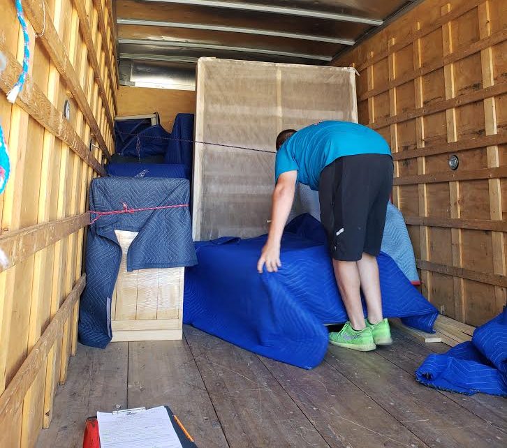 Mover wrapping furniture in moving blankets inside the truck
