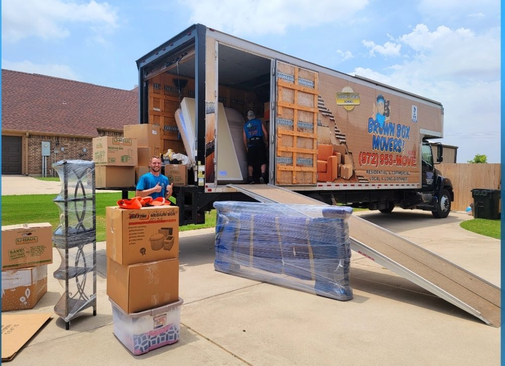Boxes and wrapped furniture beside a moving truck during a corporate relocation