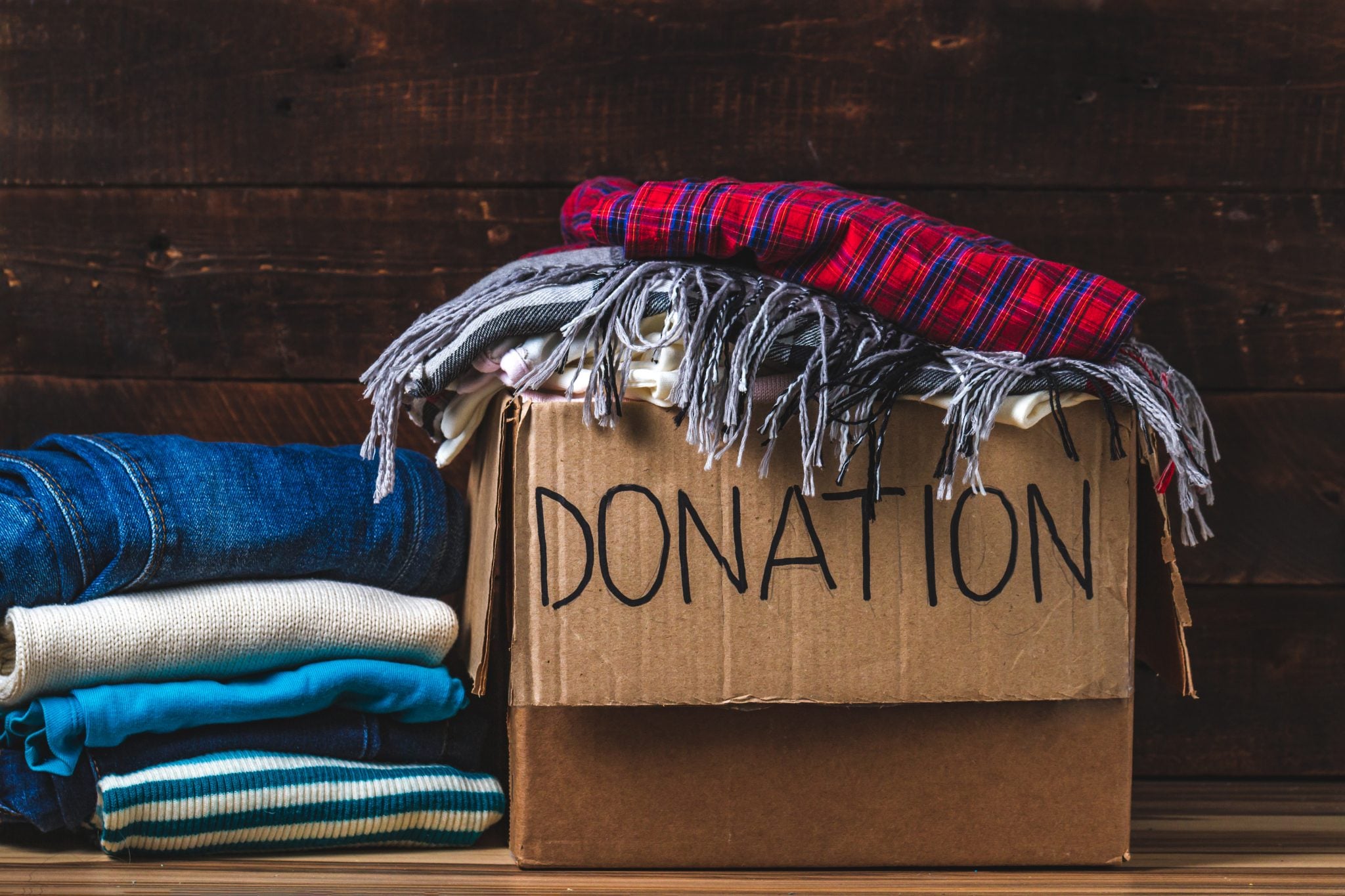 Cardboard donation box filled with folded clothes and blankets