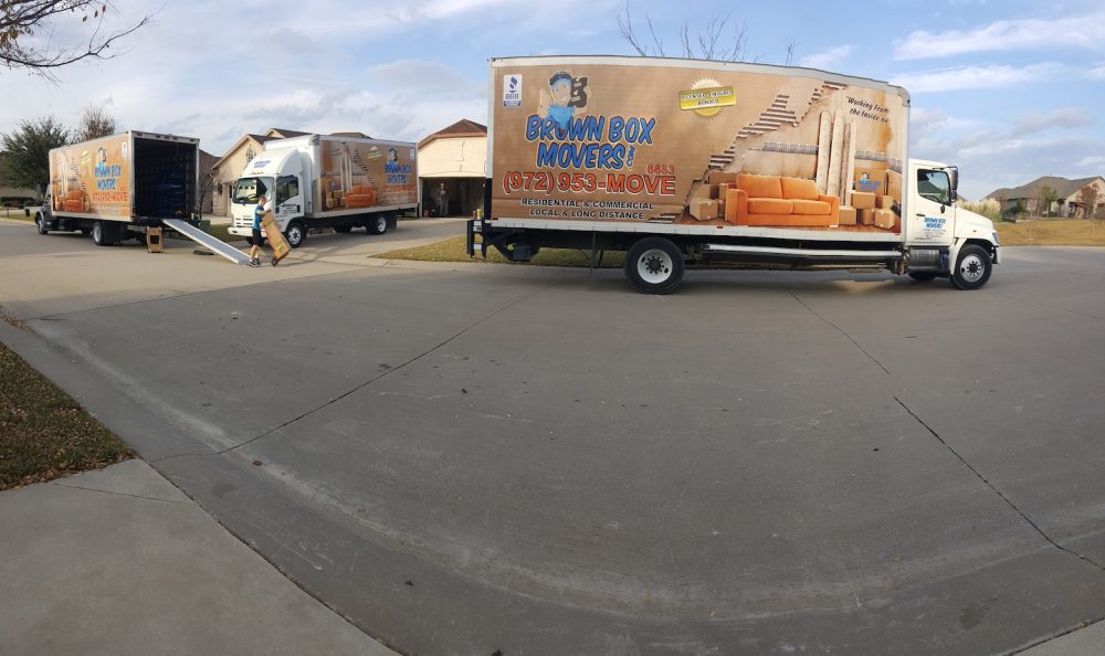 Two Brown Box Movers trucks parked in a lot