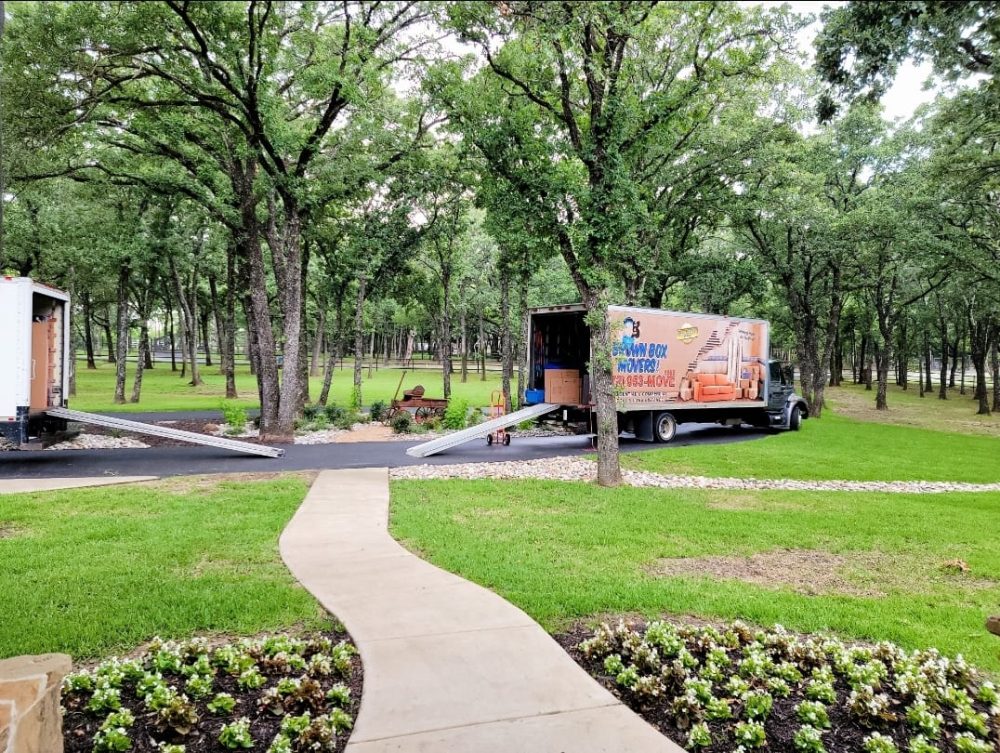 Brown Box Movers trucks parked at a tree-shaded home