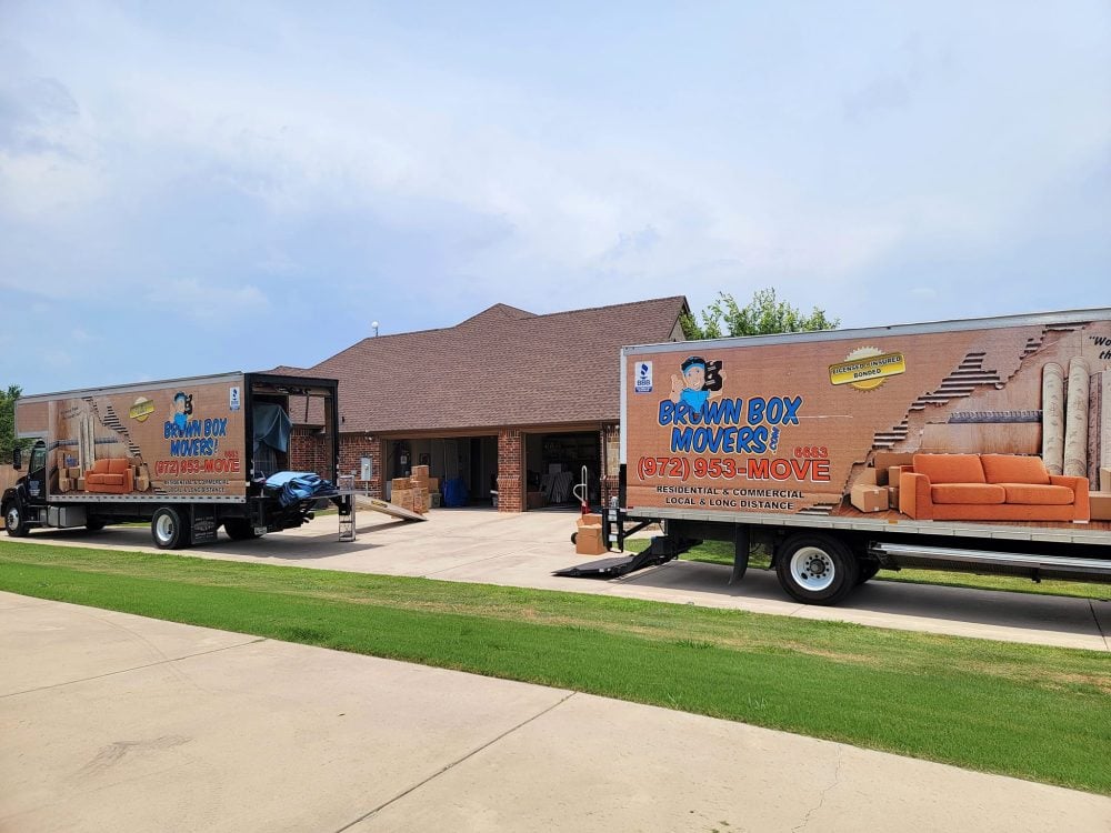 Two Brown Box Movers trucks parked in front of a home