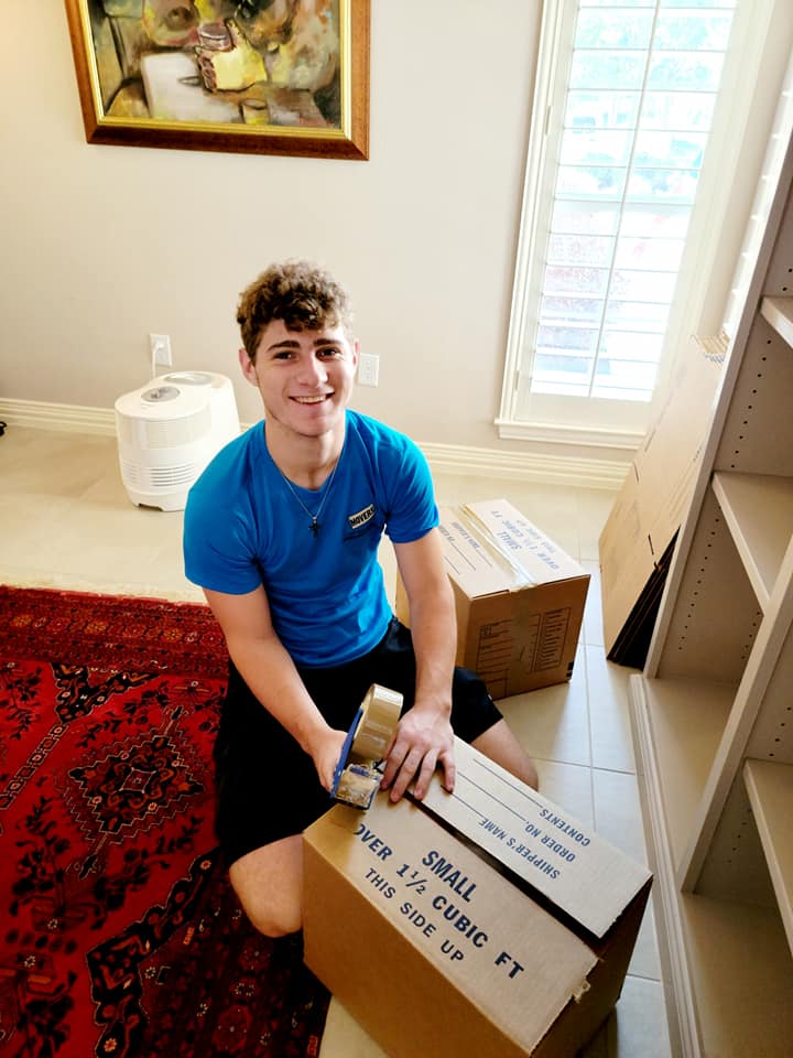 Smiling mover taping a moving box