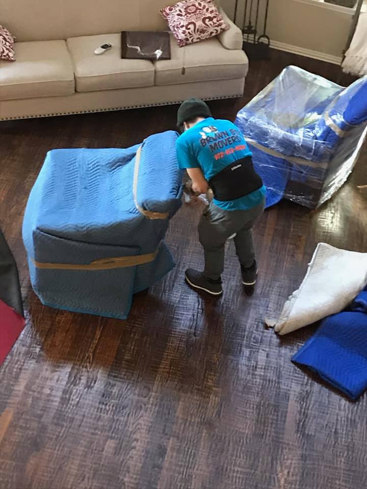 Mover wrapping furniture in blue moving blankets