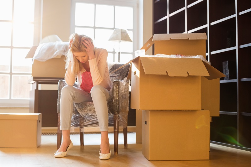 Stressed woman sitting among moving boxes