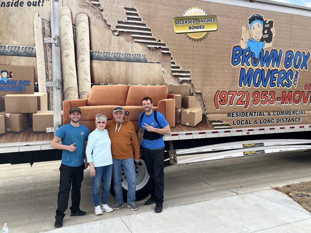 Brown Box Movers crew posing with customers in front of the moving truck