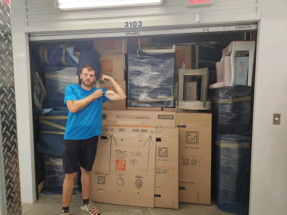 Mover inside a storage unit with packed boxes and wrapped valuables
